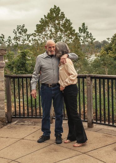 Elderly couple sharing a tender moment outdoors.