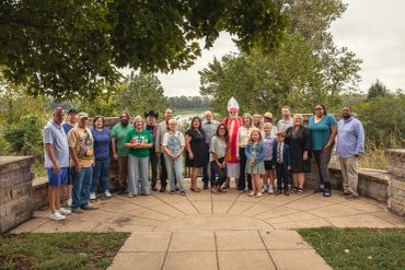 Group of people posing outdoors under leafy trees.