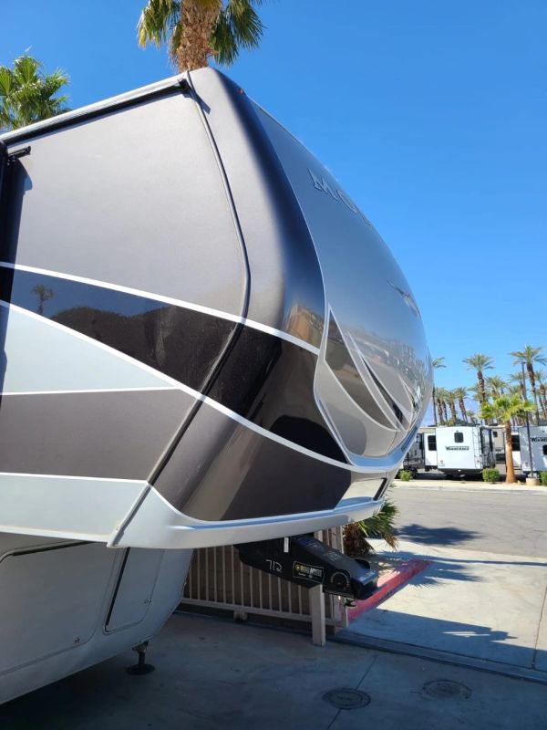 Close-up of the front of a fifth-wheel RV under blue sky.