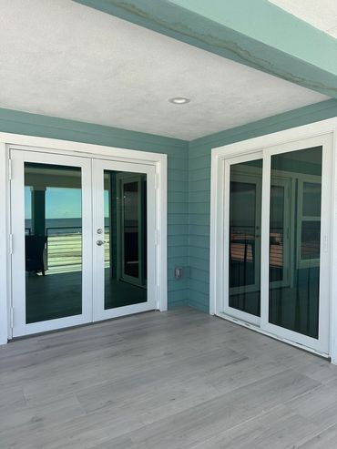 Empty balcony with glass doors and pastel blue walls.
