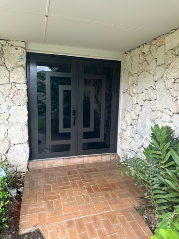 Modern black door with geometric design in stone entrance.