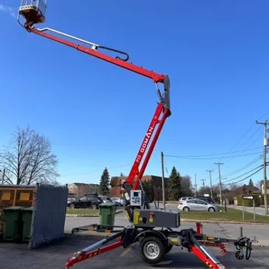 Red articulated boom lift extended outdoors under a clear blue sky.