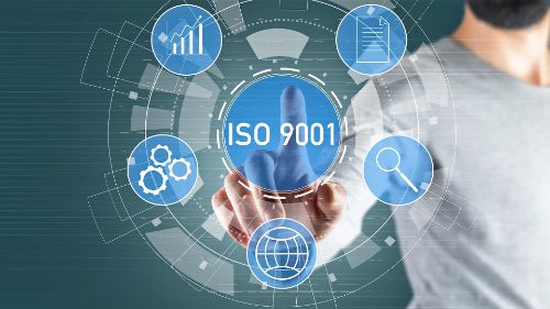 Person pointing at ISO 9001 symbol with digital interface.