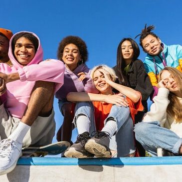 A diverse group of young friends happily posing outdoors on a sunny day.