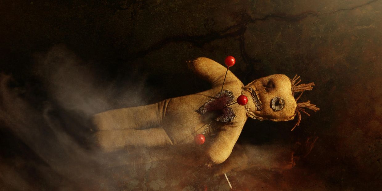 Voodoo doll with pins stuck in it.