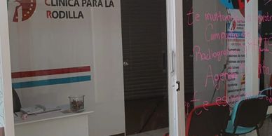 Entrada a clínica de rodilla con ventanales y sillas.