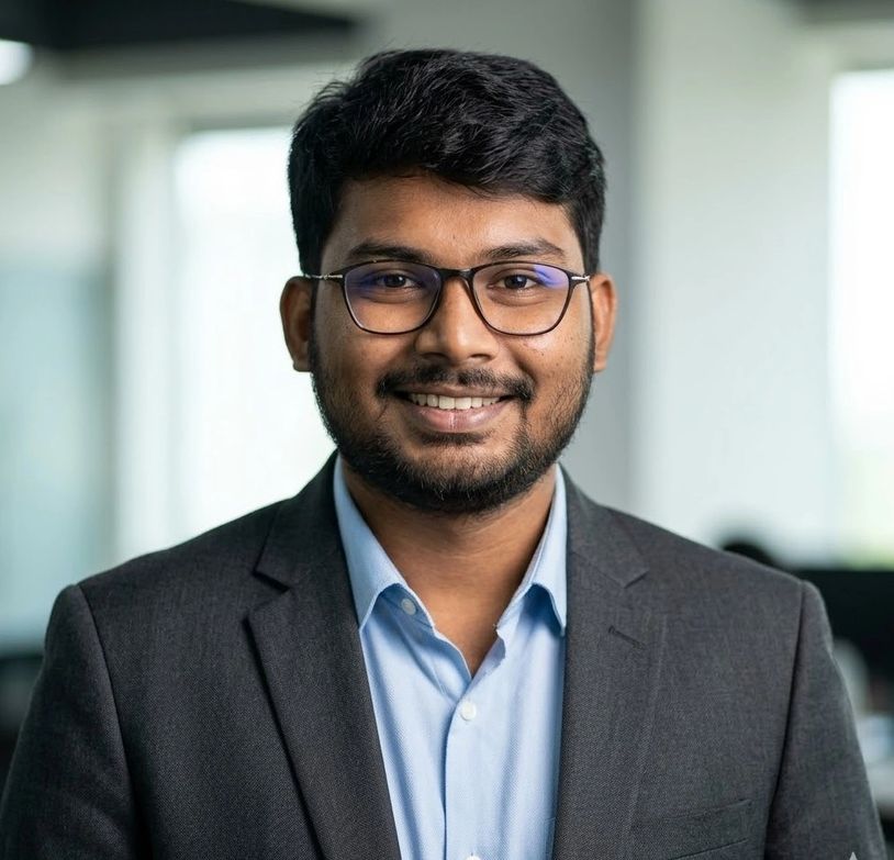 Smiling man wearing glasses and suit jacket.