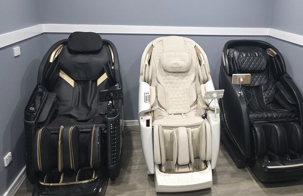 Three luxurious massage chairs in black and white colors lined up in a modern room.