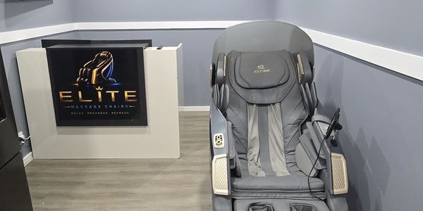 Modern massage chair in a sleek room with Elite Massage Chairs sign.