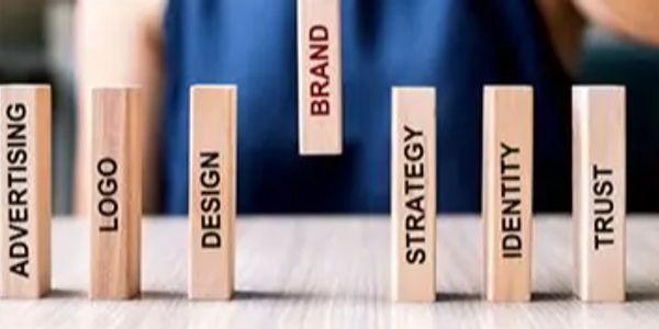 Wooden blocks labeled with marketing terms and a block labeled BRAND being placed.