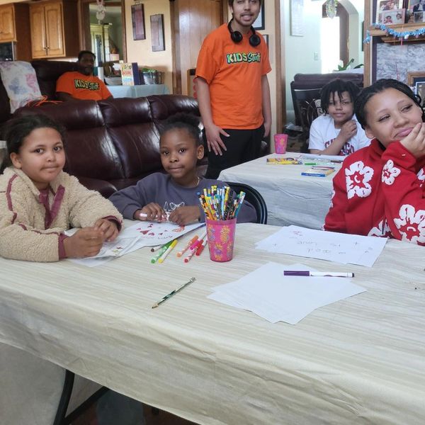 Children engaged in drawing and coloring activities at a table indoors.