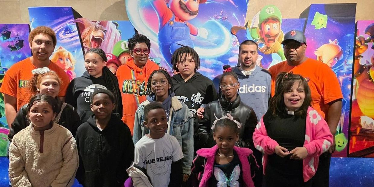 Group of people posing in front of a colorful Mario-themed backdrop.