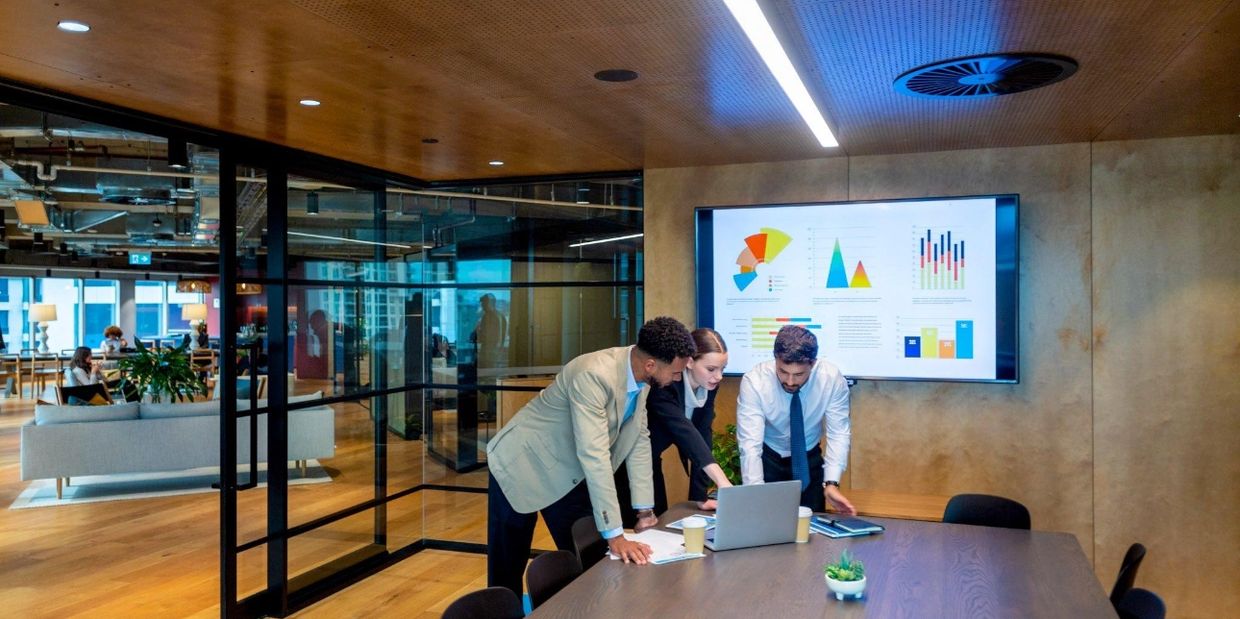 Three colleagues collaborating in a modern office meeting room.