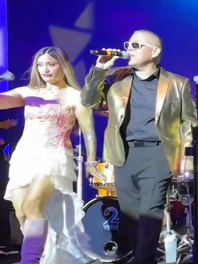Man singing with a woman dancing on stage.