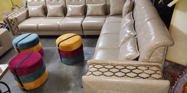 Beige leather sectional sofa with colorful round ottomans.