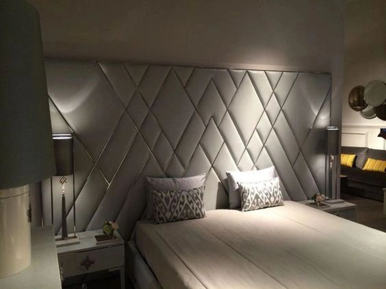Modern bedroom with geometric padded headboard and soft lighting.