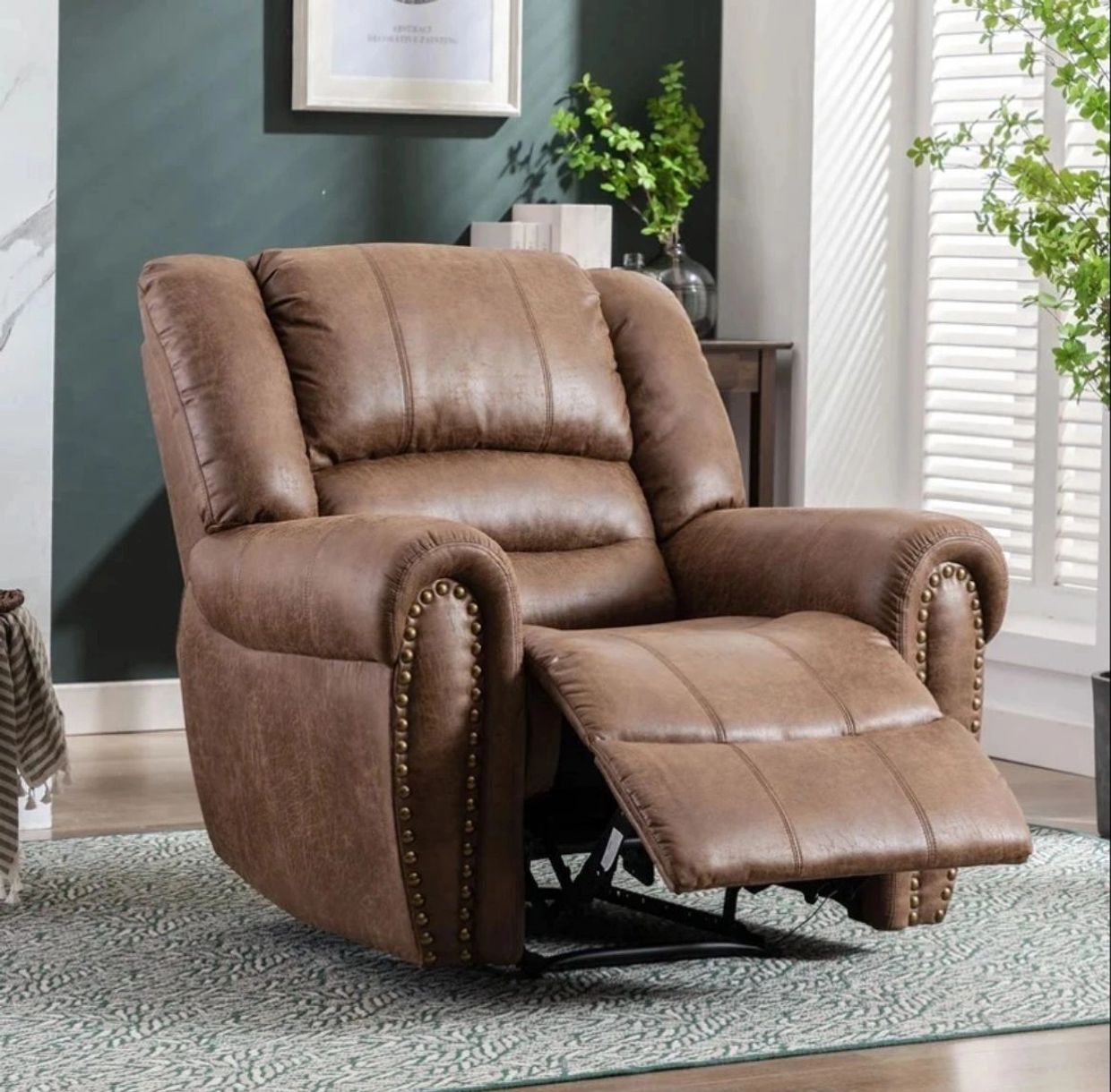 Brown leather recliner chair with brass nailhead trim in a cozy living room.