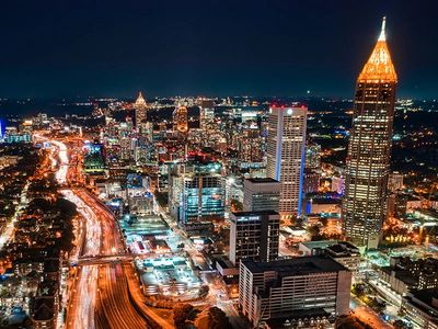 A vibrant city skyline at night with illuminated skyscrapers and busy highways.