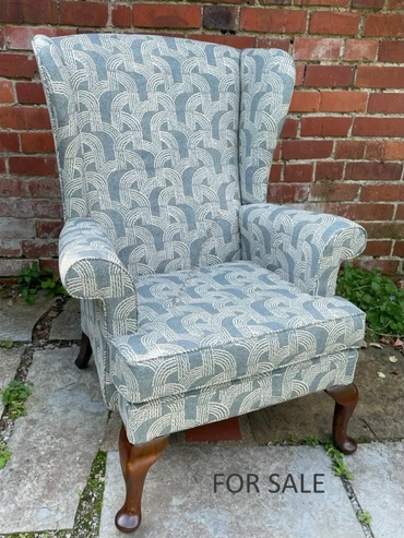 Upholstered wingback chair with wooden legs for sale.
