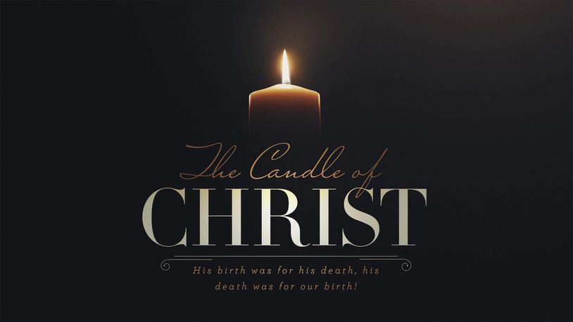A lit candle with a religious message about Christ's birth and death.