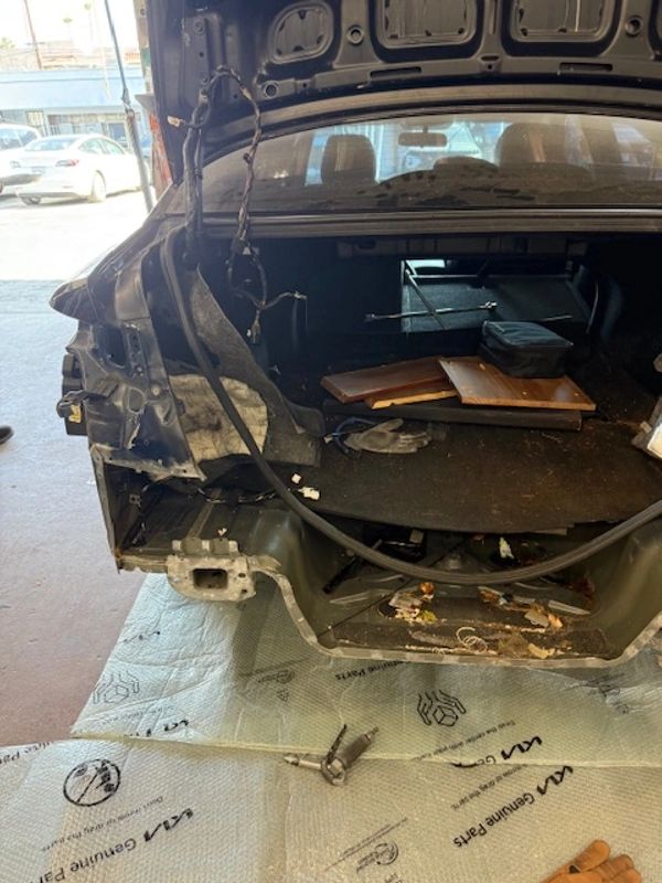 Partially disassembled car trunk with exposed interior and removed rear panel.