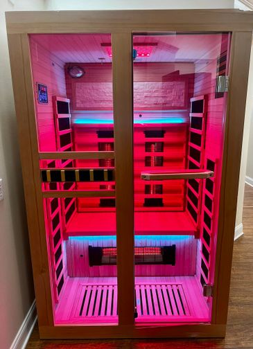 Modern infrared sauna with vibrant pink and blue LED lighting.