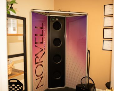 A Norvell Professional tanning booth with purple lighting inside.