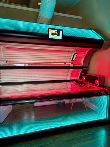 Modern tanning bed with colorful LED lights in a room.