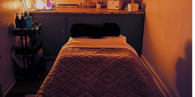 Cozy massage room with warm lighting and a neatly made massage table.
