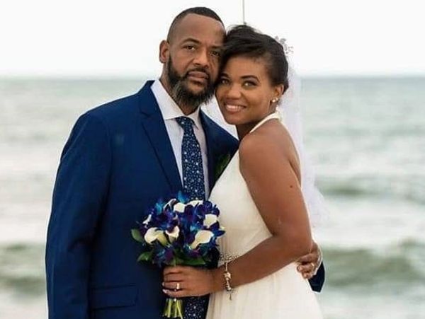 Newlywed couple posing happily by the beach on their wedding day.