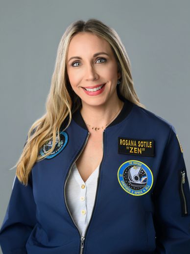 Woman in a navy blue astronaut jacket smiling.