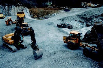 Construction vehicles working on a rocky excavation site.