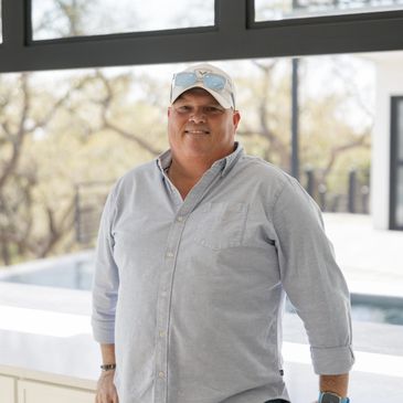 Man smiling wearing a light blue shirt and cap indoors.