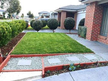 Well-maintained front yard with trimmed spherical bushes and a neat lawn.