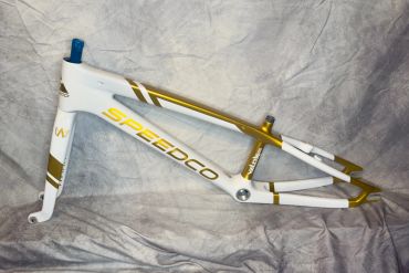 White and gold SPEEDCO bicycle frame against a gray background.