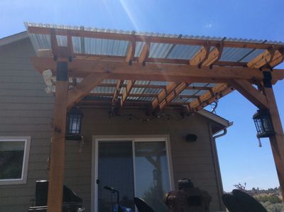Wooden pergola with transparent roof panels attached to a house patio.