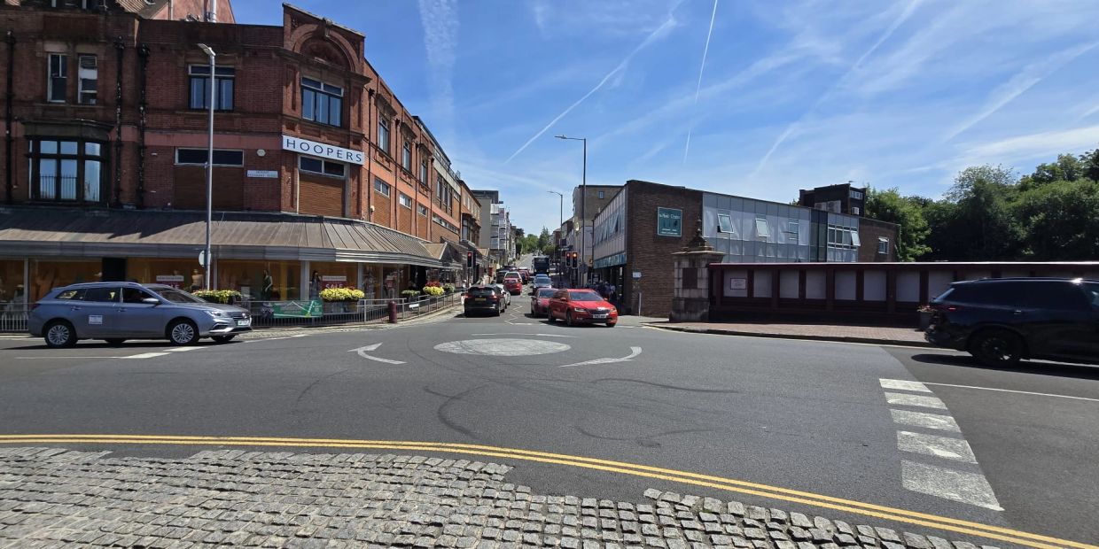 A bright day on a city street with vintage buildings and cars.