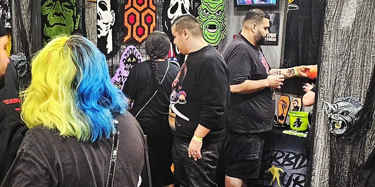 People browsing a booth with horror-themed decorations and masks.