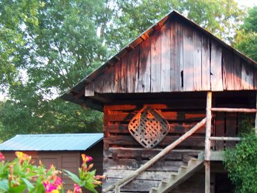 Rustic wooden cabin surrounded by greenery and flowers.