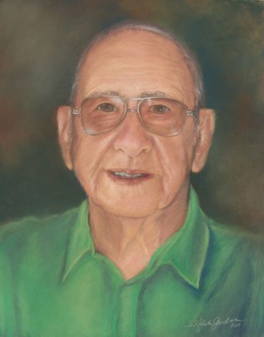 Portrait of an elderly man in glasses and green shirt.