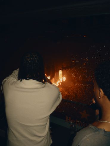 Two people watching a concert with bright stage lights in the distance.