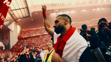 Athlete celebrating victory wrapped in a flag in a packed stadium.