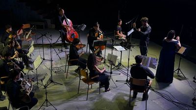 An orchestra performing on stage with a conductor and soloist.