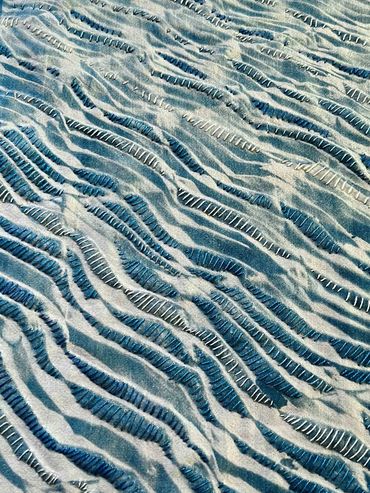 Printed cyanotype with hand embroidery resembling rippled water.