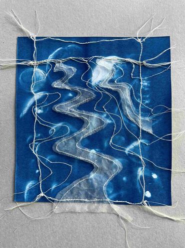 Machine embroidery depicting water flowing through a creek.