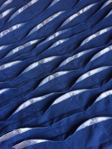 Blue and silver pleated and tucked fabric with machine stitching, detail image.