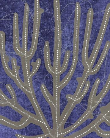 Detail image of cream machine stitched coral on blue fabric.