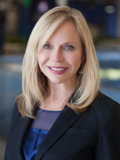 Professional woman with blonde hair in business attire smiling.
