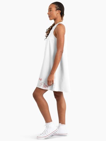 Woman in a white sleeveless dress and white sneakers.