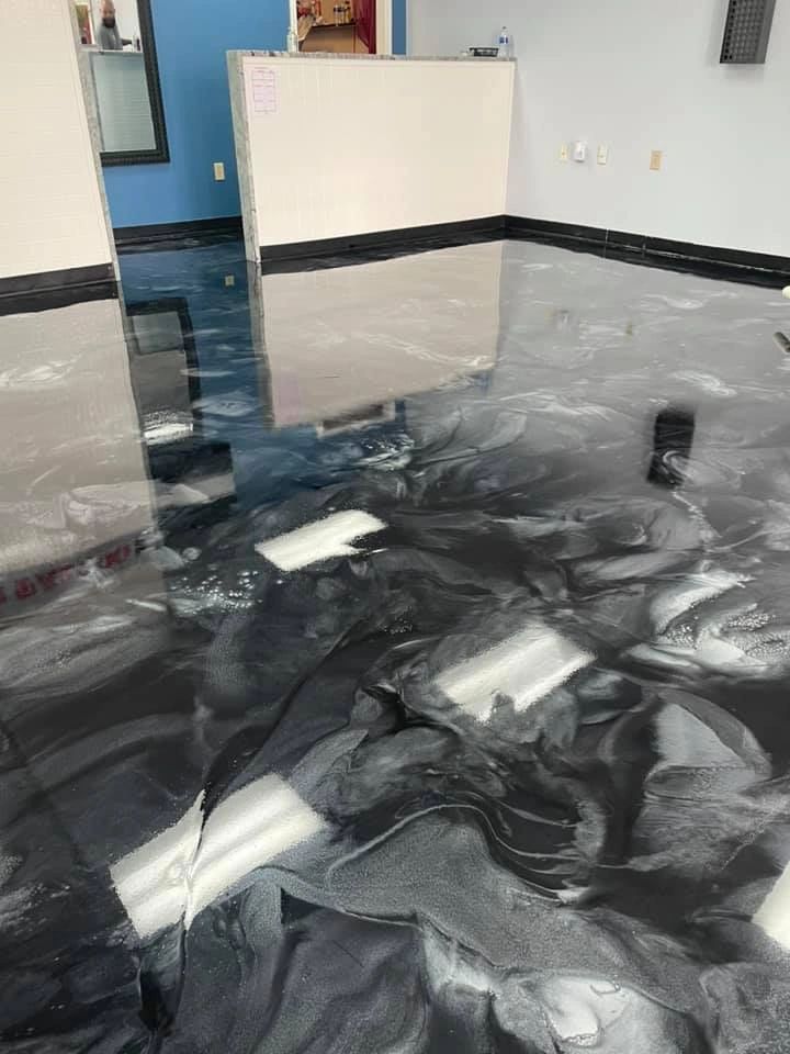 Shiny black and white swirled epoxy floor in an empty room.